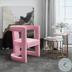 a pink chair sitting in front of a window next to a table with flowers on it