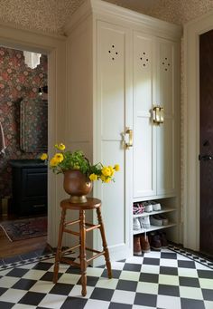 a vase with yellow flowers sitting on top of a stool in front of a door