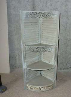 the corner shelf is painted white and has an ornate design on it's sides