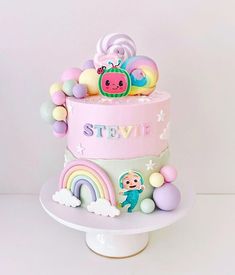 there is a pink cake decorated with animals and rainbows on the top tier,