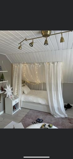 a bedroom with white curtains and lights on the ceiling