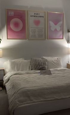 a bed with white sheets and pillows in a bedroom next to two pictures on the wall