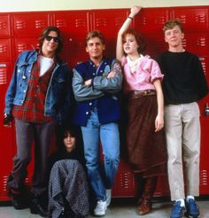 four people standing next to each other in front of lockers