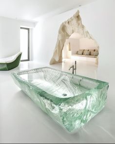 a glass sink in a white room with a large rock behind it and a green tub