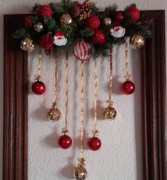 christmas decorations hanging on the wall in front of a mirror with red and gold ornaments