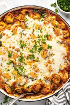 a casserole dish filled with pasta and cheese, garnished with parsley