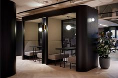 an office lobby with chairs and tables in the center, surrounded by large black pillars