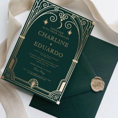 a green and gold wedding card with a wax stamp on it, next to an envelope