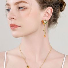 Infuse your style with a touch of nature-inspired elegance with our Golden Plum Drop Earrings, a striking accessory that captures the essence of botanical beauty. These exquisite earrings are meticulously crafted, featuring delicate plum motifs adorned with vibrant orange and green enamel. Each earring showcases a cluster of golden plums and leaves, accented by petite white blossoms that cascade down on fine golden chains. Whether you're dressing up for a special occasion or adding a unique touc Elegant Orange Flower Earrings, Elegant Orange Flower Earrings For Gift, Golden Plum, Everyday Wear Jewelry, Astrology Jewelry, Plum Flowers, Flower Drop Earrings, Fruit Jewelry, Nature Earrings