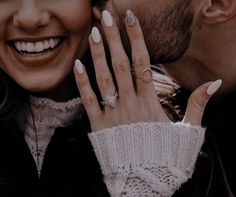 a man and woman are holding each other close to their face with rings on their fingers