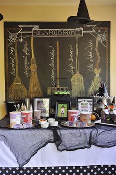 a table topped with lots of halloween decorations and witches hats on top of blackboards