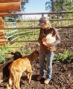 a woman standing next to two goats in a pen