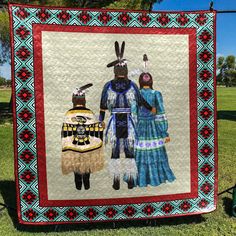 an image of two people in native clothing on a quilted wall hanging from a wire fence