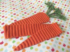 two knitted carrots laying on top of a polka dot covered bed sheet with green stems sticking out of them