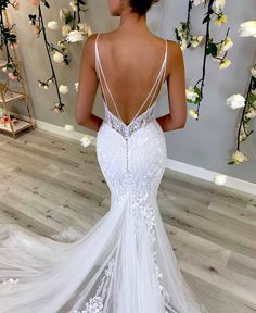 a woman in a white wedding dress looking back at the camera with flowers behind her