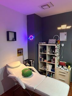 a room that has a bed, desk and shelves in it with neon lights on the wall