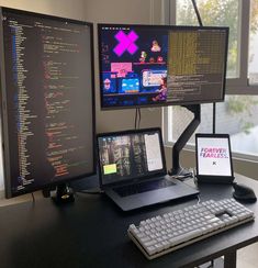 two computer monitors sitting on top of a desk next to a keyboard and monitor screen