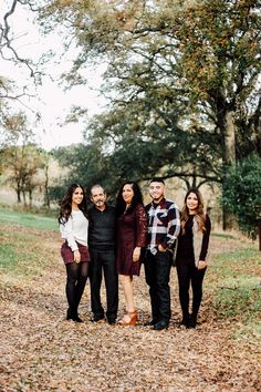 a group of people standing next to each other in front of some trees and leaves