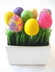 some fake grass and colorful balls in a white vase