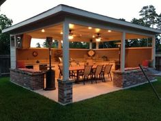 an outdoor kitchen and dining area is lit up at night with lights on the ceiling