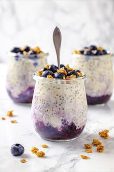 two glasses filled with blueberry cheesecake overnight oatmeal next to a spoon