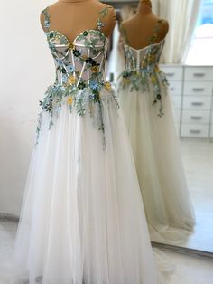 two dresses on mannequins in front of a mirror