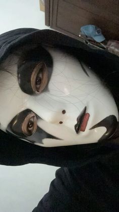 a person wearing a white mask and black hoodie with eyes wide open in front of a mirror