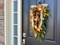 a wreath hanging on the front door of a house decorated with autumn leaves and berries