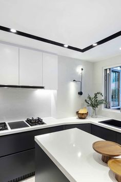 a modern kitchen with white counter tops and black accents