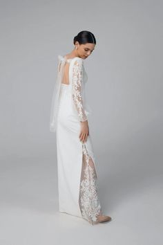 the back of a woman wearing a white wedding dress with sheer sleeves and lace detailing