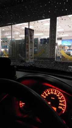 the dashboard of a car in front of a store window with raindrops on it