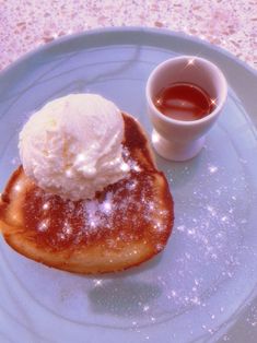 a blue plate topped with pancakes covered in powdered sugar next to a cup of tea