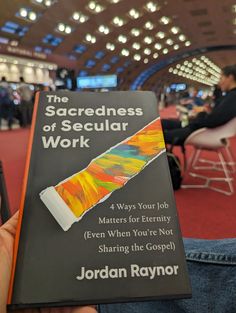 someone holding up a book about the sacredness of secular work in their hand