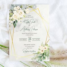 a wedding card with white flowers and greenery