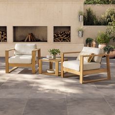 two wooden chairs sitting next to each other in front of a fire place with potted plants