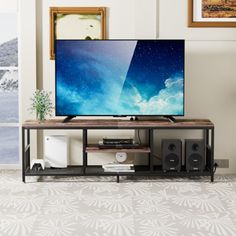 a flat screen tv sitting on top of a wooden stand in front of a window