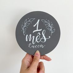 a person holding up a sticker with the words 1 mes luca written on it