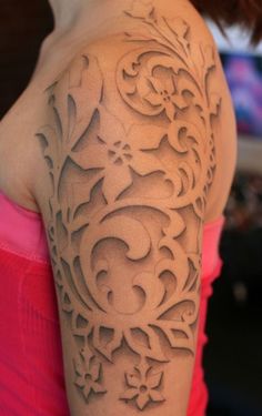 a woman's arm with an intricate tattoo design on the back of her shoulder