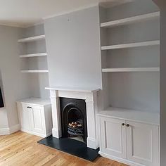 an empty living room with built in bookshelves and fireplace