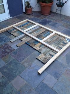 a wooden frame laying on the ground next to a potted plant in front of a door