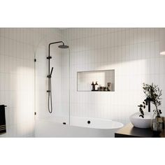 a white bathtub sitting next to a sink and mirror in a bathroom with tiled walls