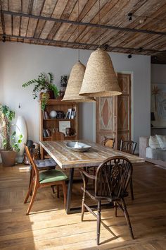 a dining room table with two lamps hanging from it's ceiling and chairs around it