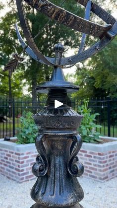 a large metal object sitting on top of a stone slab in front of a fence