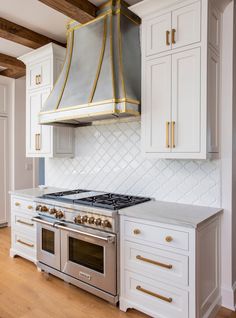 a stove top oven sitting inside of a kitchen next to white cabinets and wooden floors