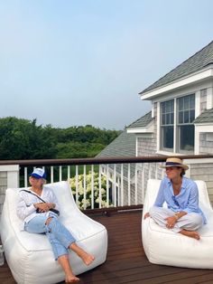 two people sitting on bean bags on a deck next to each other and one person wearing a hat