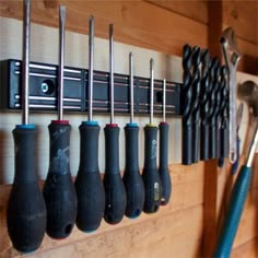 there are many tools hanging on the wall with hooks and wrenches attached to it