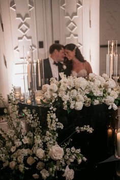 a bride and groom kissing in front of candles