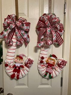 two christmas wreaths hanging on the front door decorated with candy canes and elf dolls