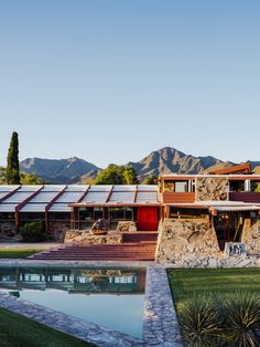 a house with a pool in front of it and mountains in the backround