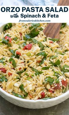 pasta salad with spinach and feta in a white bowl on top of a table